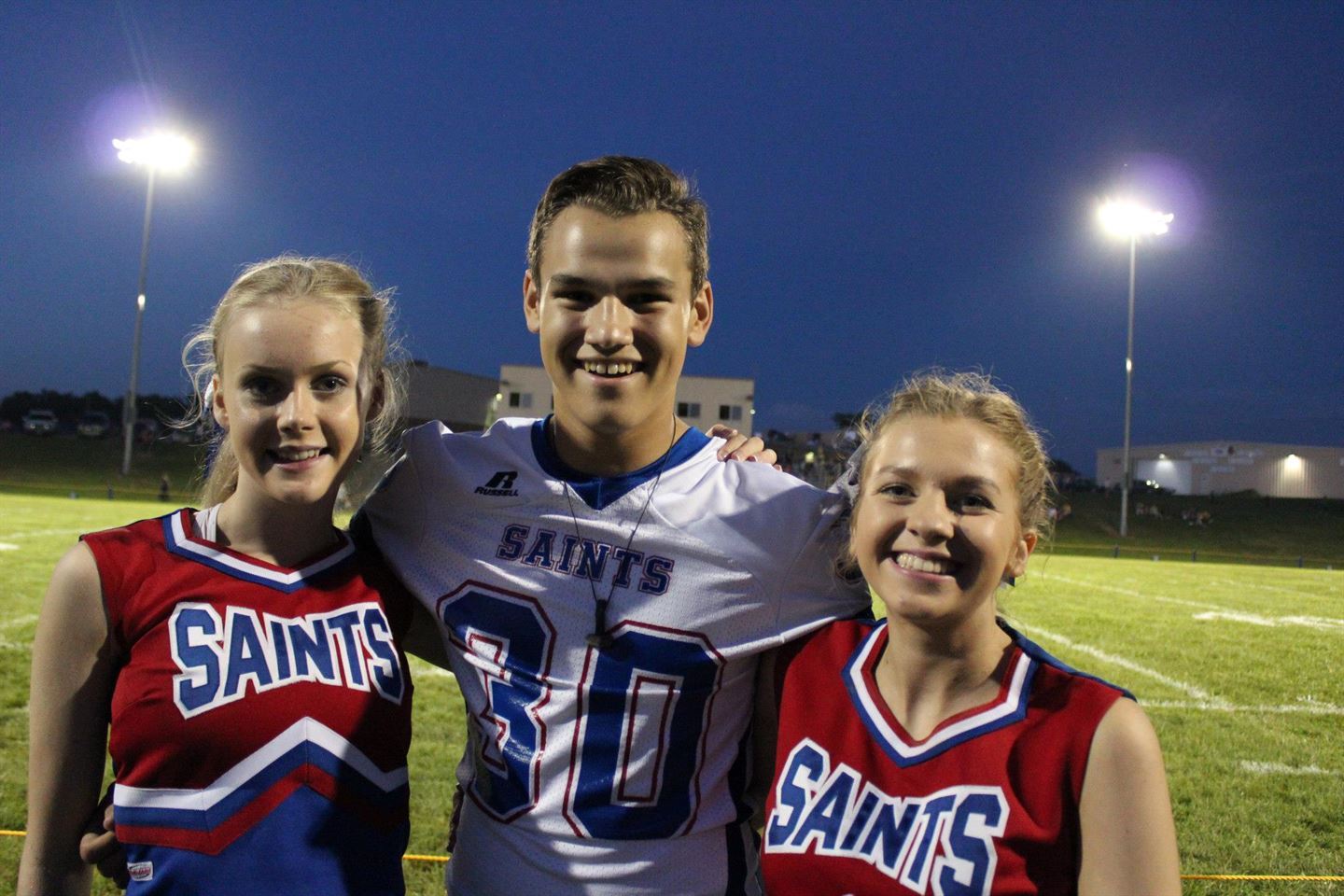 To jenter i cheerleading-kler med ein gut i amerikansk fotball-drakt