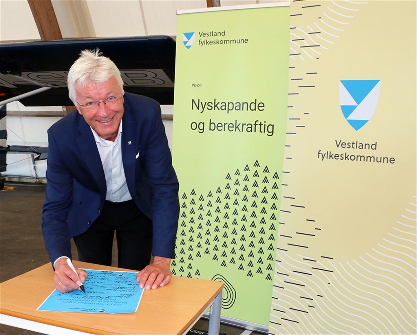 Fylkesordførar Jon Askeland signerer avtalen etter samarbeidsmøtet om satsing på fly utan utslepp: «Eg vil vere med på å gjere Vestlandet til eit pionerområde for nullutsleppsfly».