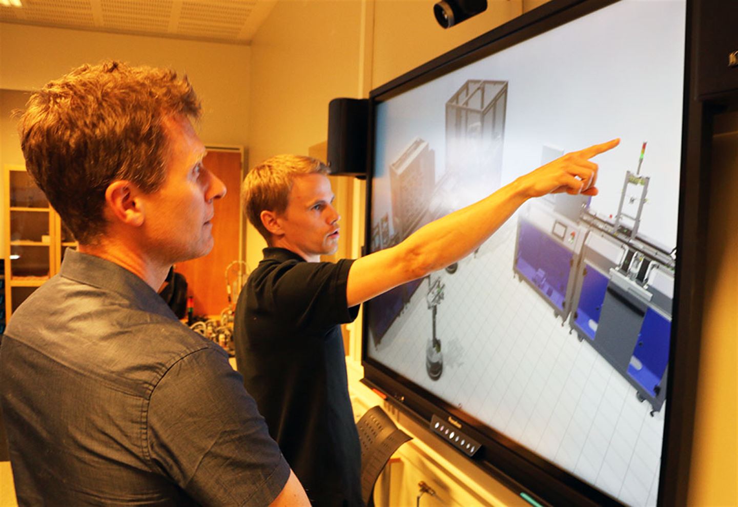 Olav Vangen hos den tyske leverandøren Festo Didactic viser lærar Bjørnar Seim korleis dei kan teste programmet på skjerm for å sjå korleis det fungerer.