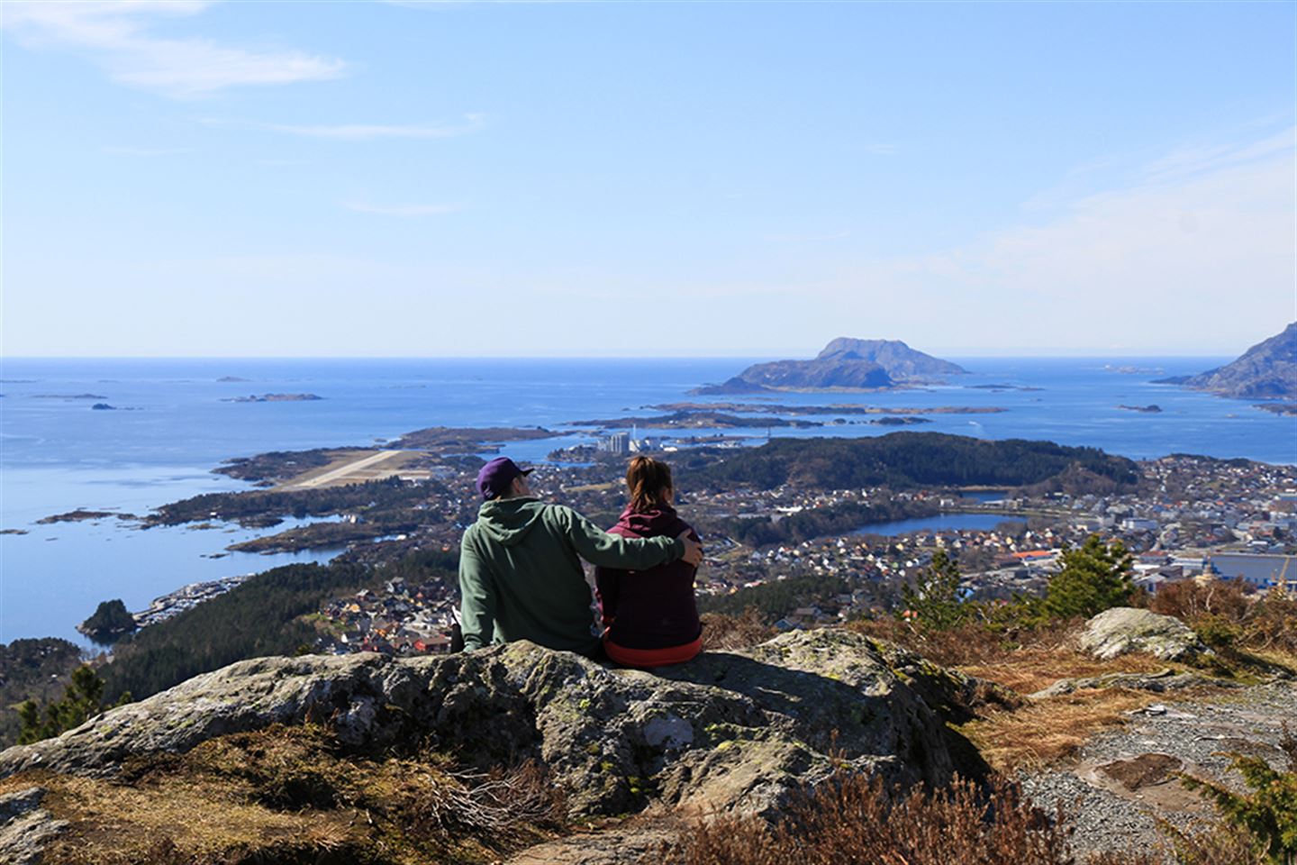 foto av to ungdomar som sit på toppen av Brandsøyåsen med utsikt over Florø