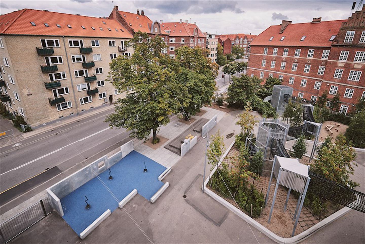 Foto frå skulegarden ved Amager Fælled skole i København. Illustrasjon av nyskapande aktivitetsanlegg.