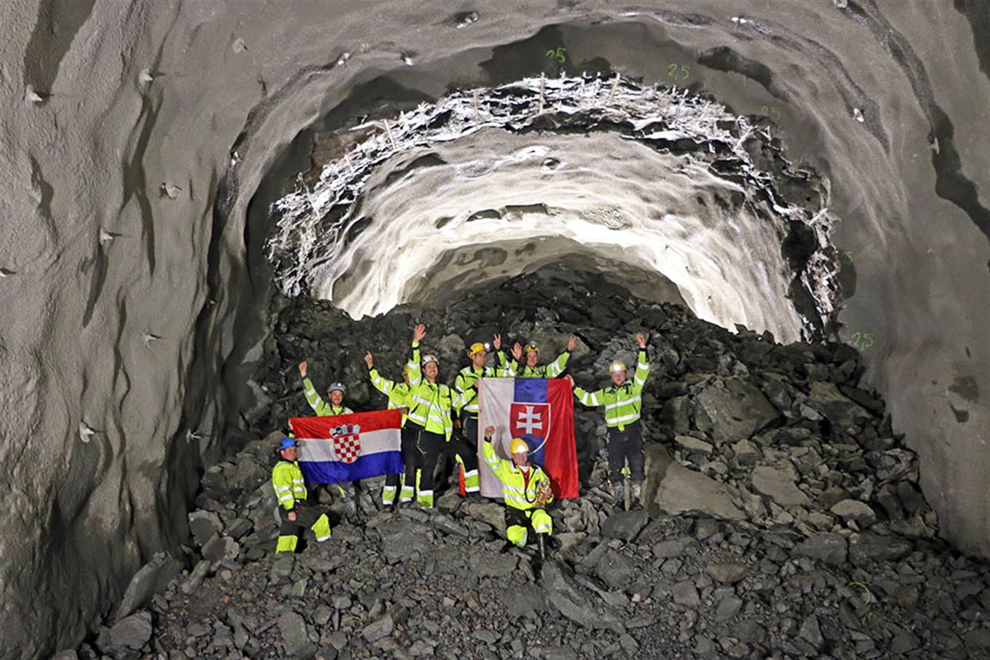 Etter gjennomslaget jublar tunnelarbeidarane på den siste salven. Flagga markerer at arbeidarane er frå Kroatia og Slovenia. (foto: Bjarte Brask Eriksen/Vestland fylkeskommune)