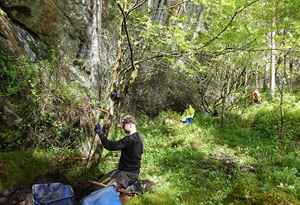 Arkeologar i arbeid under ein steinheller. Foto.