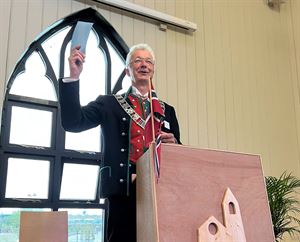 Fylkesordførar i bunad på talarstol. Foto.