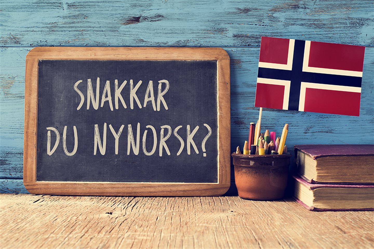 Foto av tavle med skrifta Snakkar du nynorsk? Norsk flagg ved sidan av tavla.