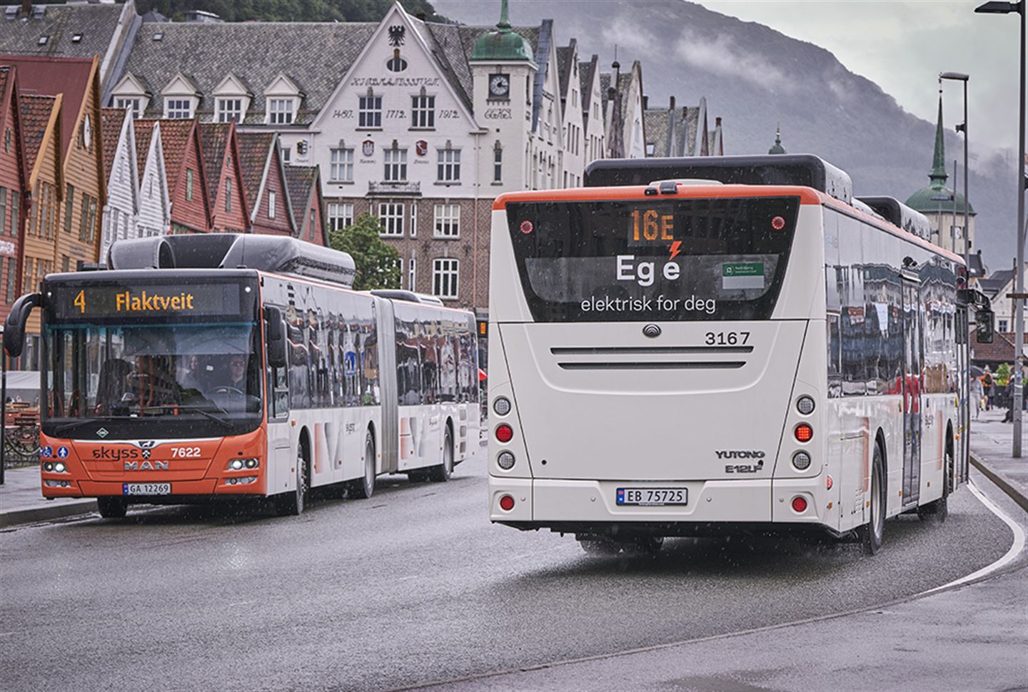 foto av to bussar som møter kvarandre på Bryggen i Bergen. På bakruta på den eine står det Eg e elektrisk for deg