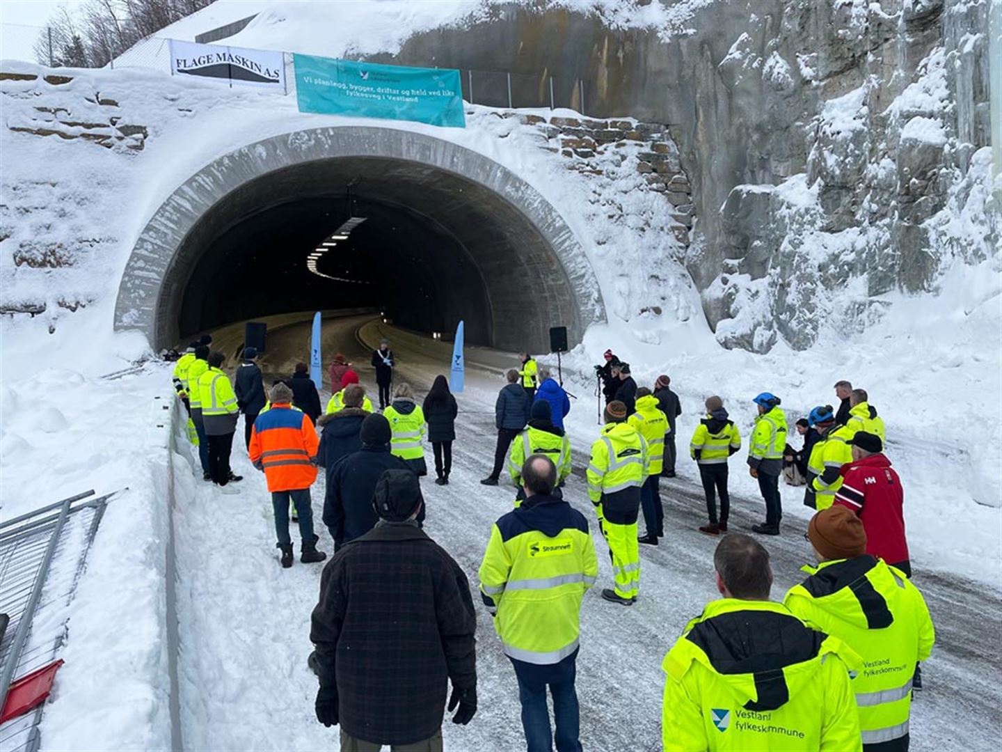 Mennesker i gule arbeidsjakkar er publikum når Ljoteli-tunnelen vert opna. Foto.