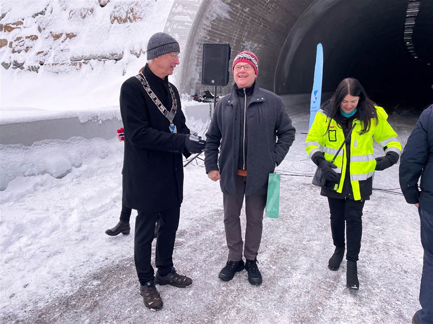 Fylkesordførar Askeland med ordførarkjede i samtale framfor tunnelopninga. foto.