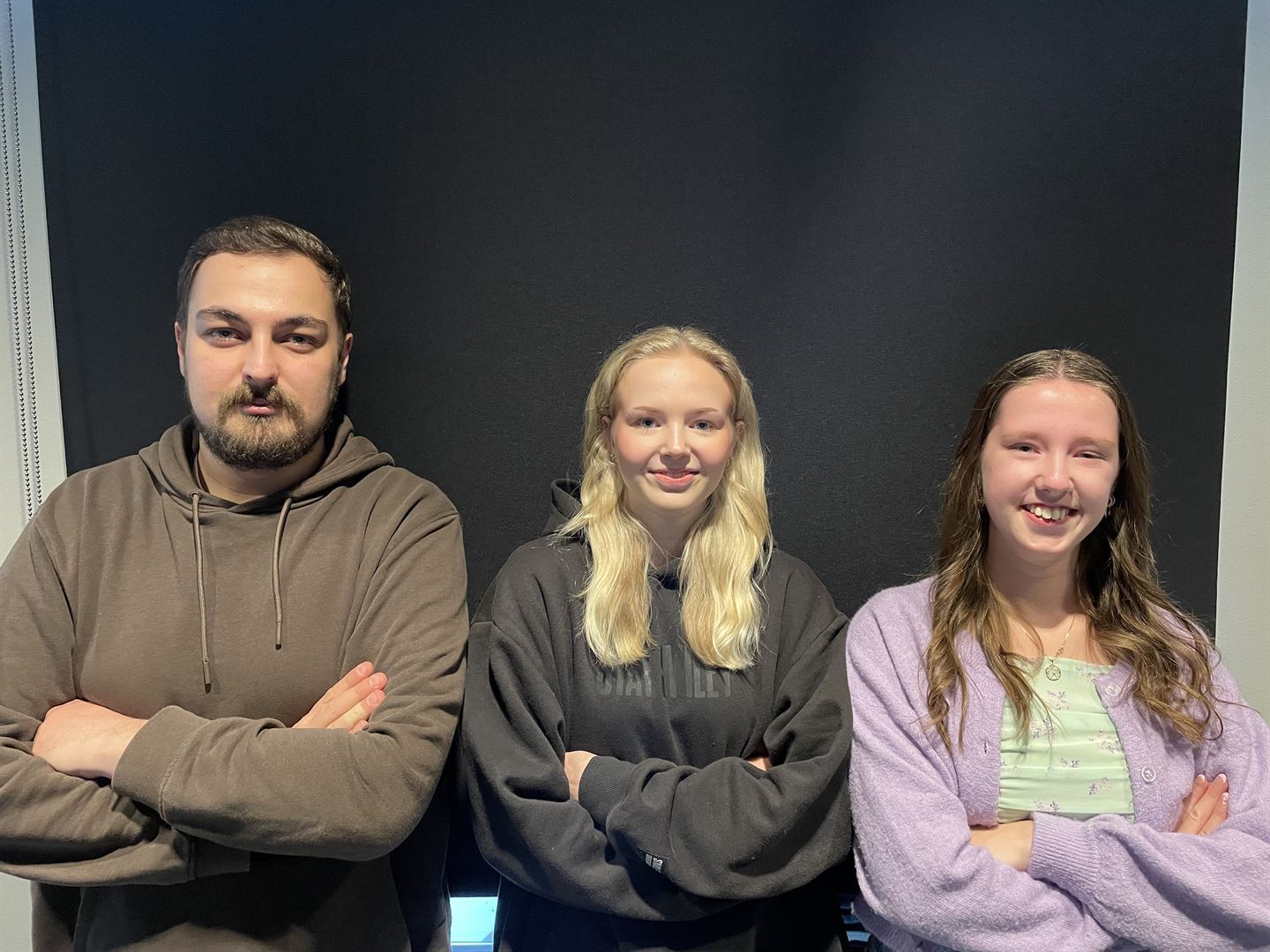 Tre elevar med armane i kryss mot ein vegg.