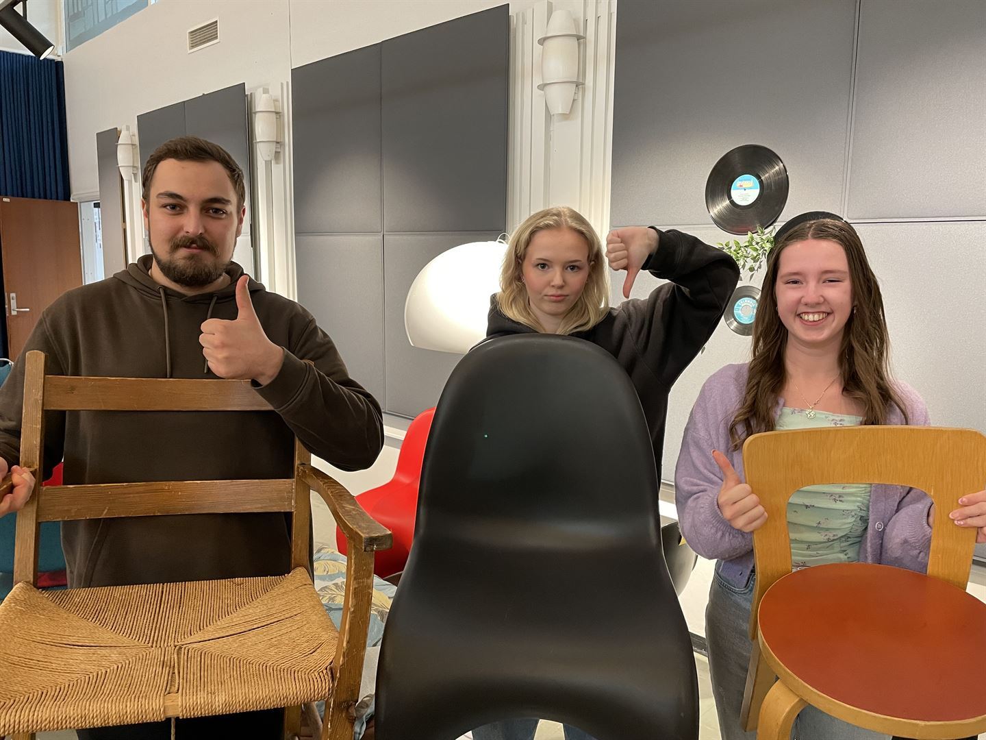 Tre elever held kvar sin stol. To elevar held trestolar og har tommel opp, mens ein elev held ein plaststol og har tommel ned.