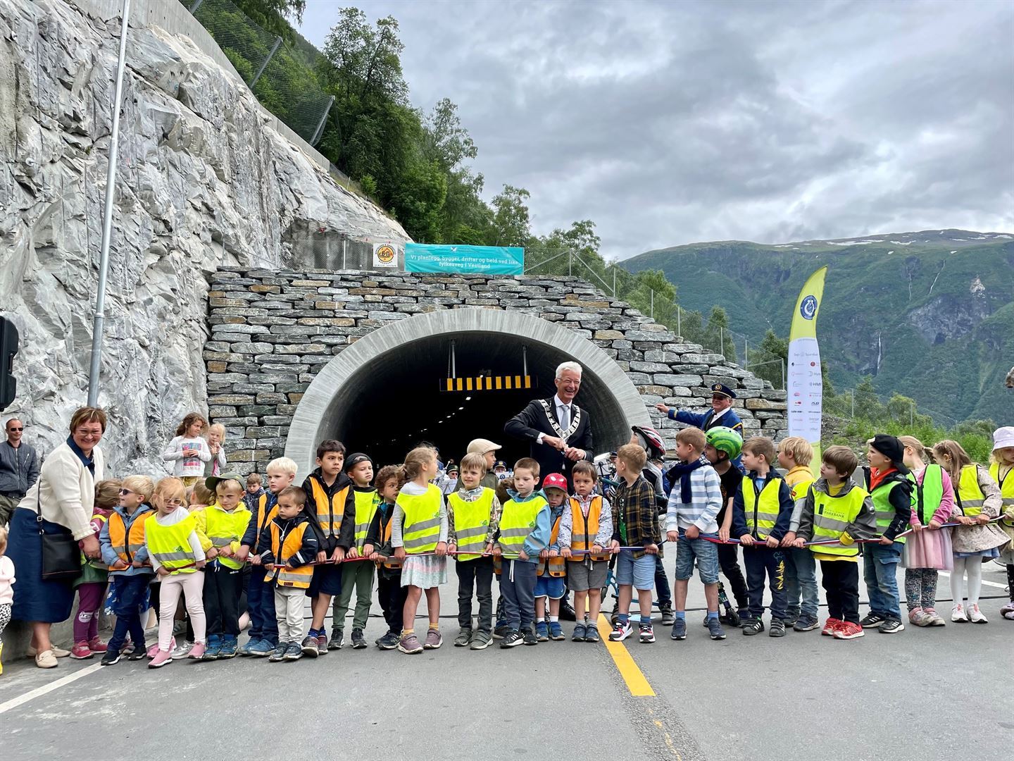 Fylkesordførar Jon Askeland og fleire barn foran tunellopninga