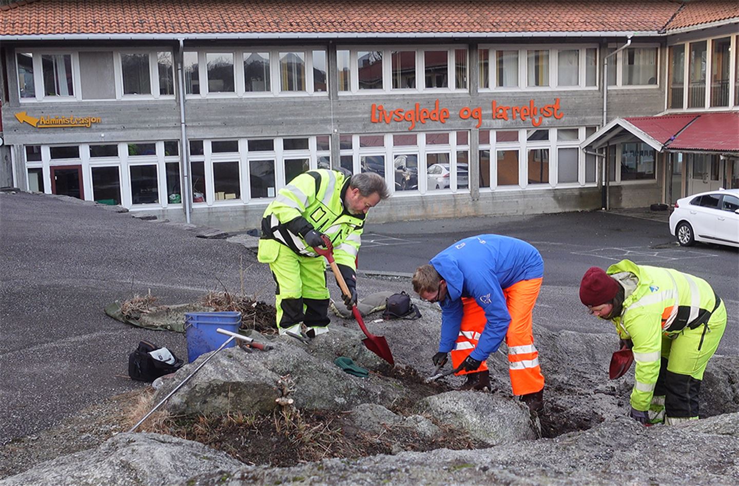 Tre arkeologar i arbeid på skuleplass.