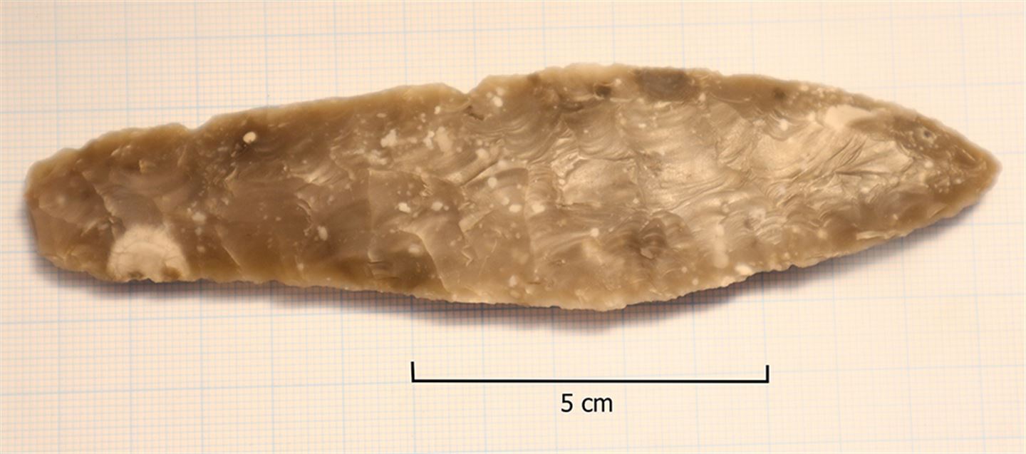 Cirka 12 cm lang flintdolk frå steinalderen.
