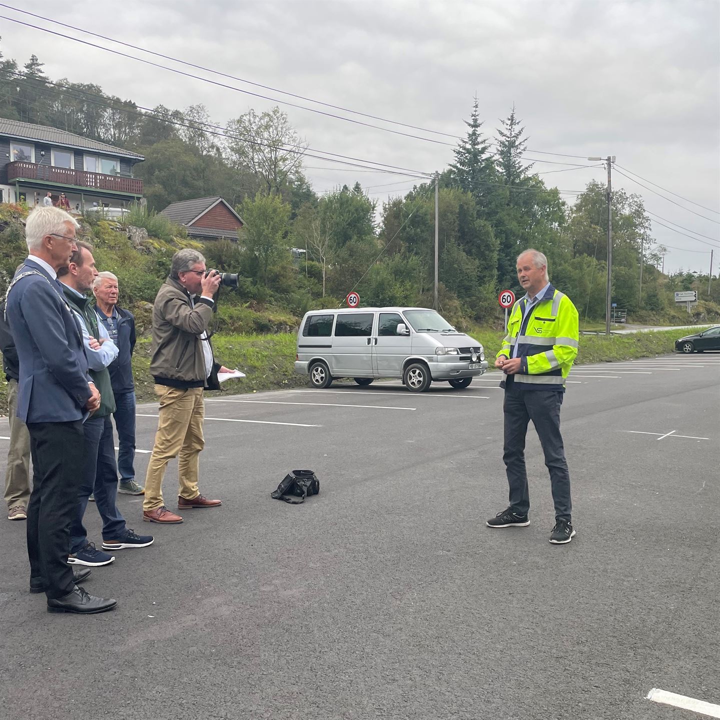 Mann som står på plassen med gul jakke og folk rundt.