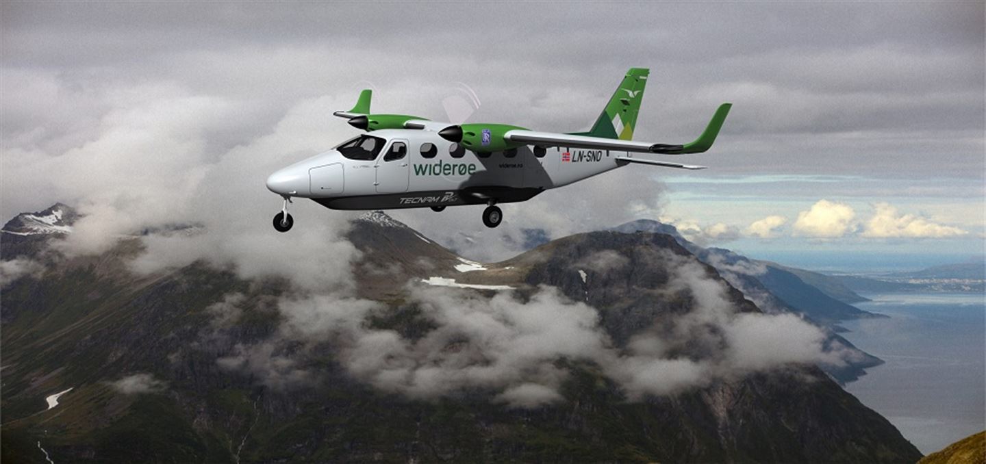Småfly i lufta med fjell i bakgrunnen.