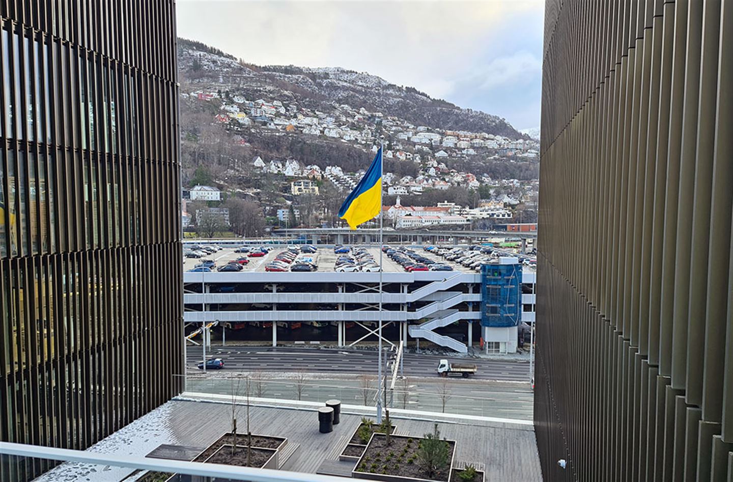 Ukrainsk flagg på flaggstang mellom to store bygningar.