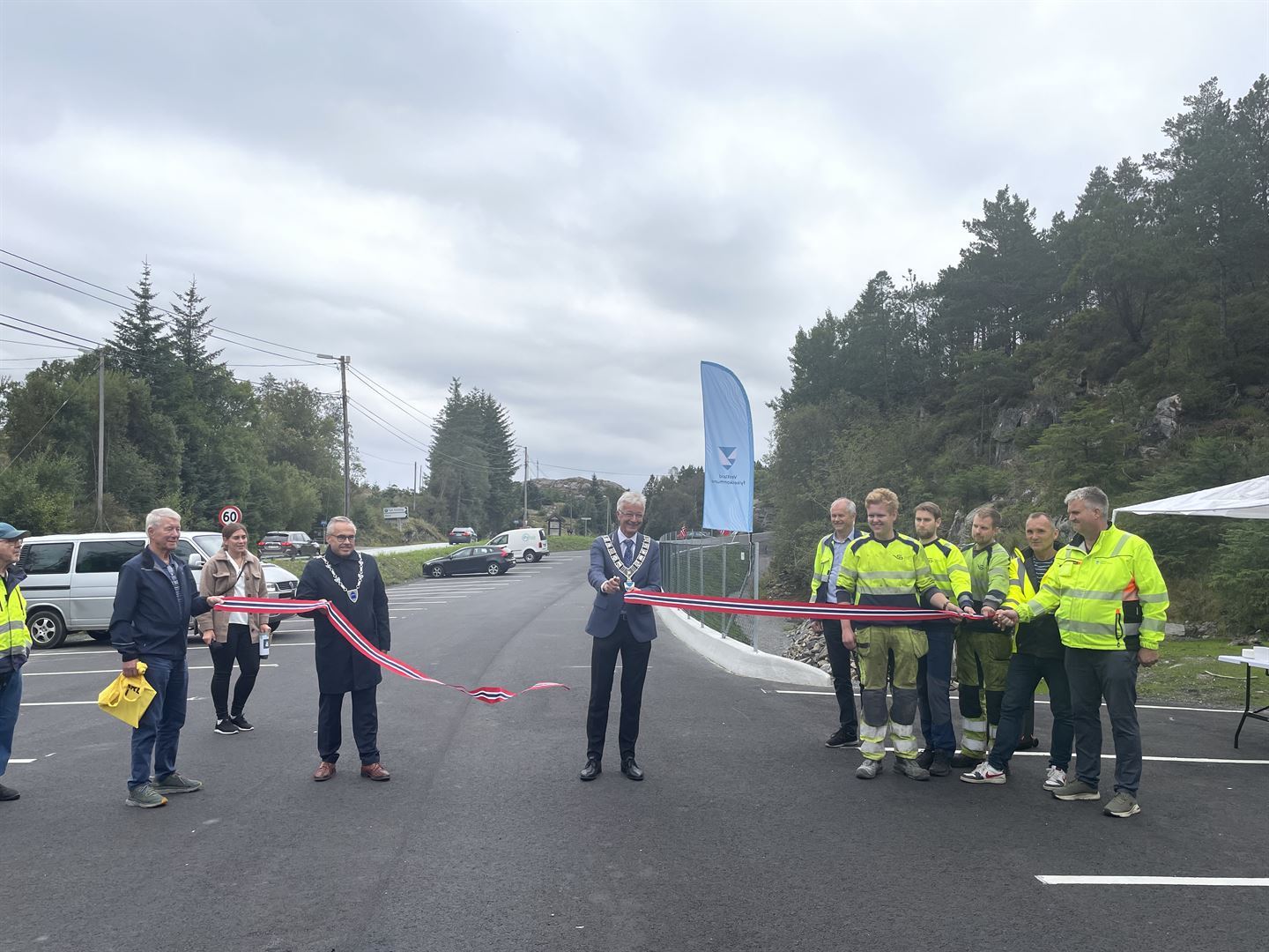 Mann som skjere ei snor og folk som står på kvar side.