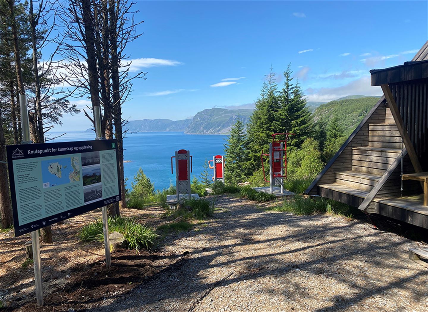 Informasjonsskilt og treningsapparat utanfor ei av dagsturhyttene. Utsikt mot lyngheiene på Stadlandet og mot havet.