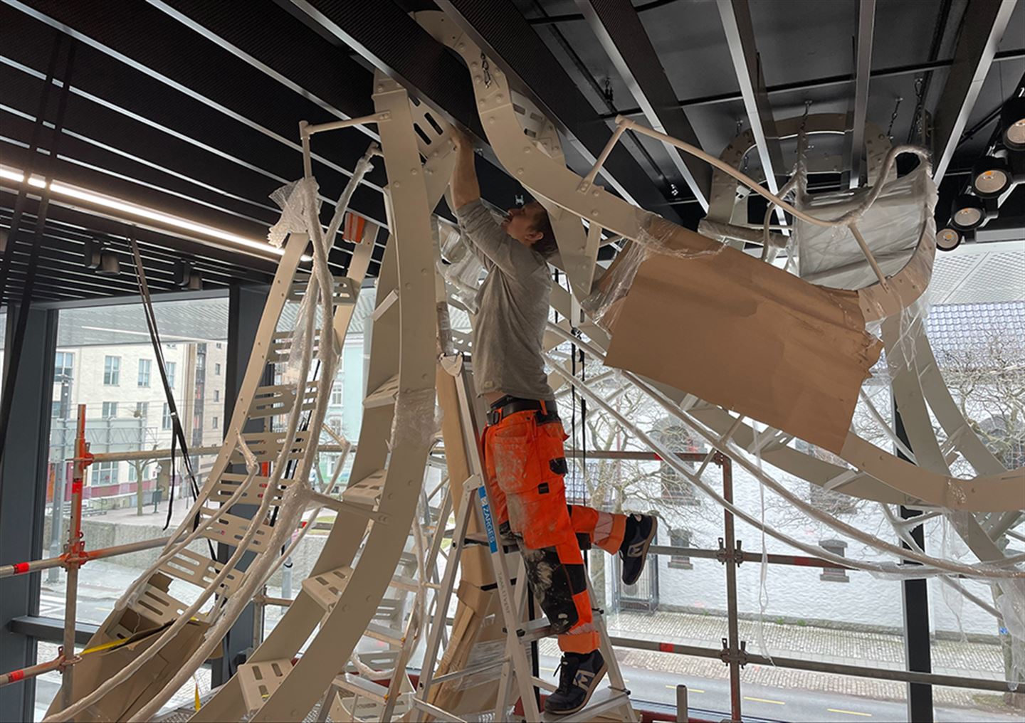 Kunstnar monterer stort kunstverk i taket på Vestlandshuset.