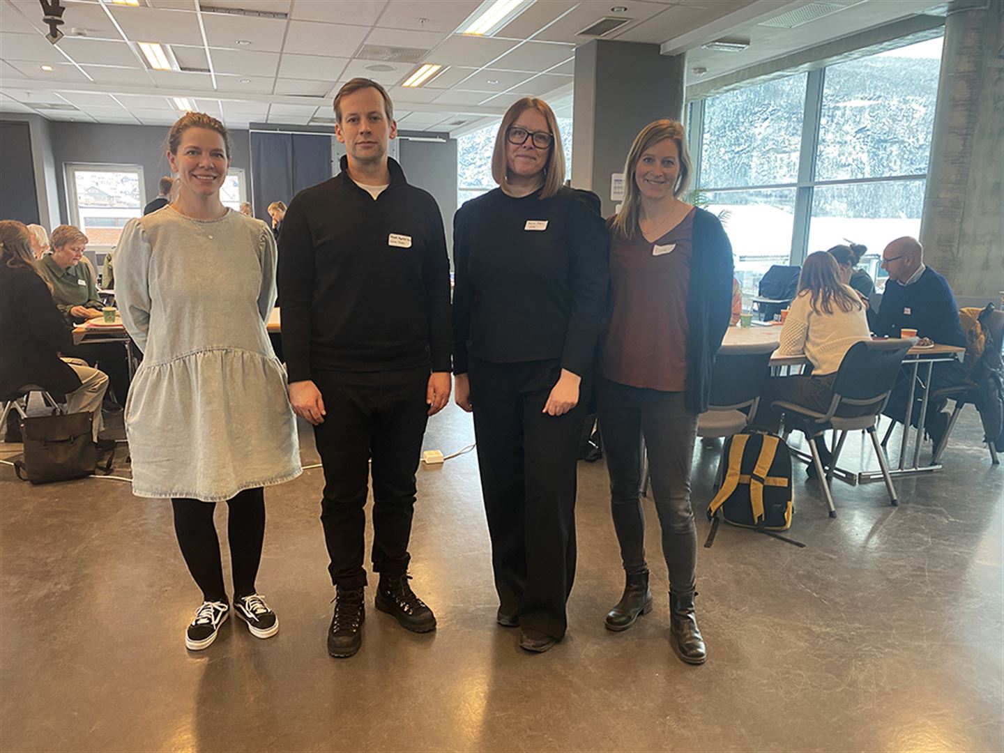 Tre kvinner og ein mann framfor eit rom med folk.