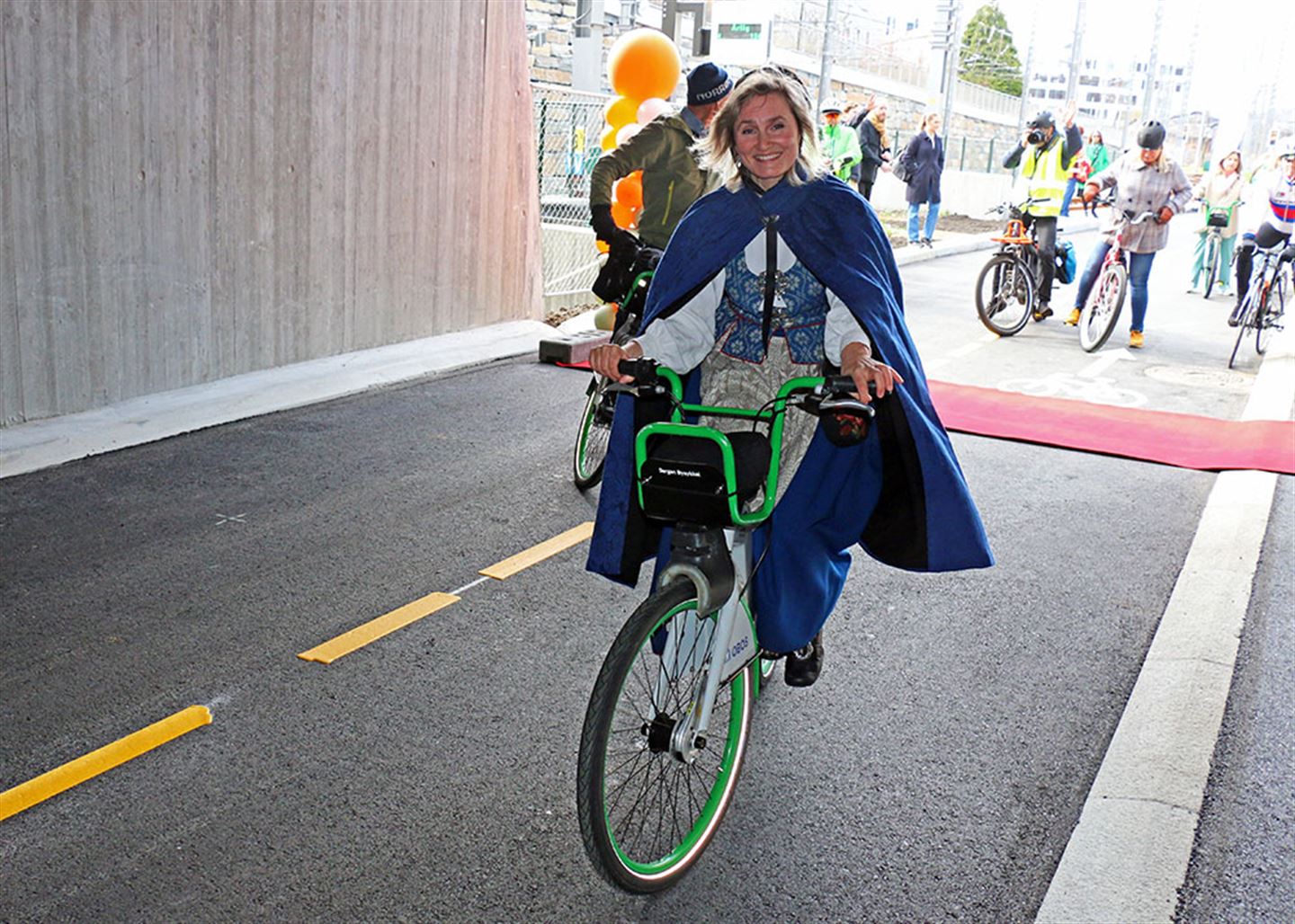 Dame i bunad på sykkel i tunnel.