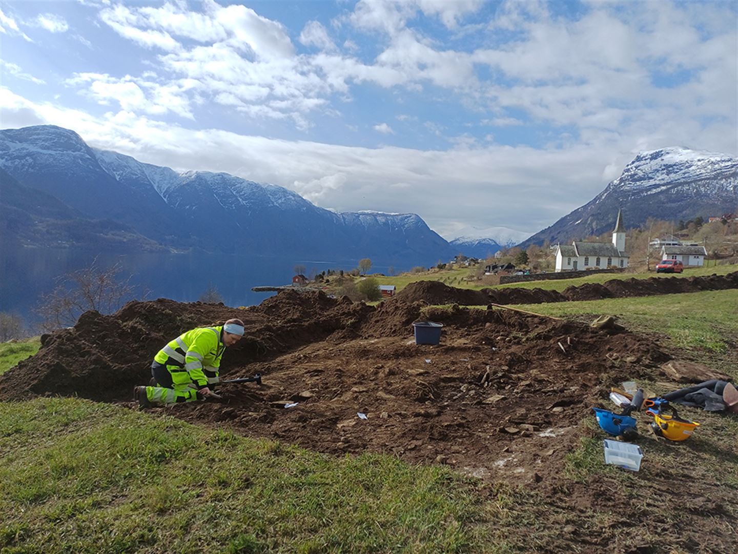 Arkeolog i ferd med å undersøke noko i jord som er graven opp.