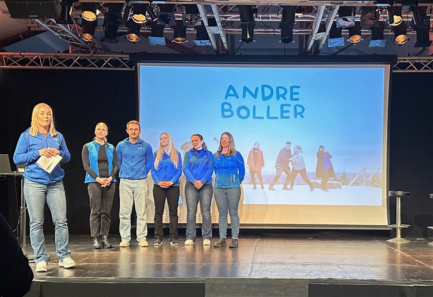 Menneske på ei scene. Bilde med teksten Andre boller i bakgrunnen.