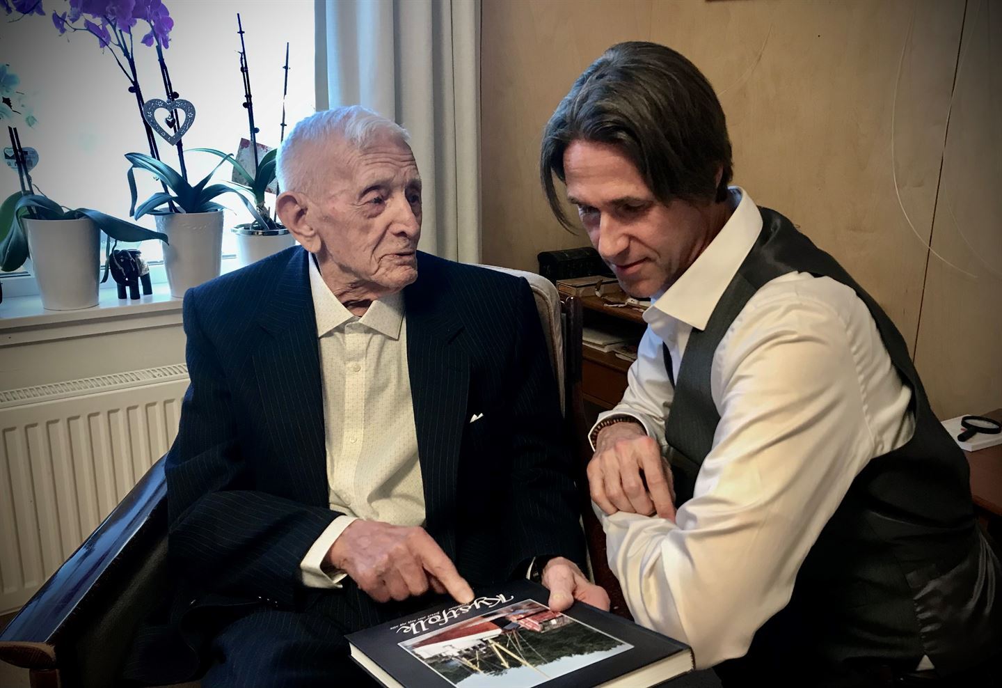 eldre og yngre  mann som ser på ei bok saman