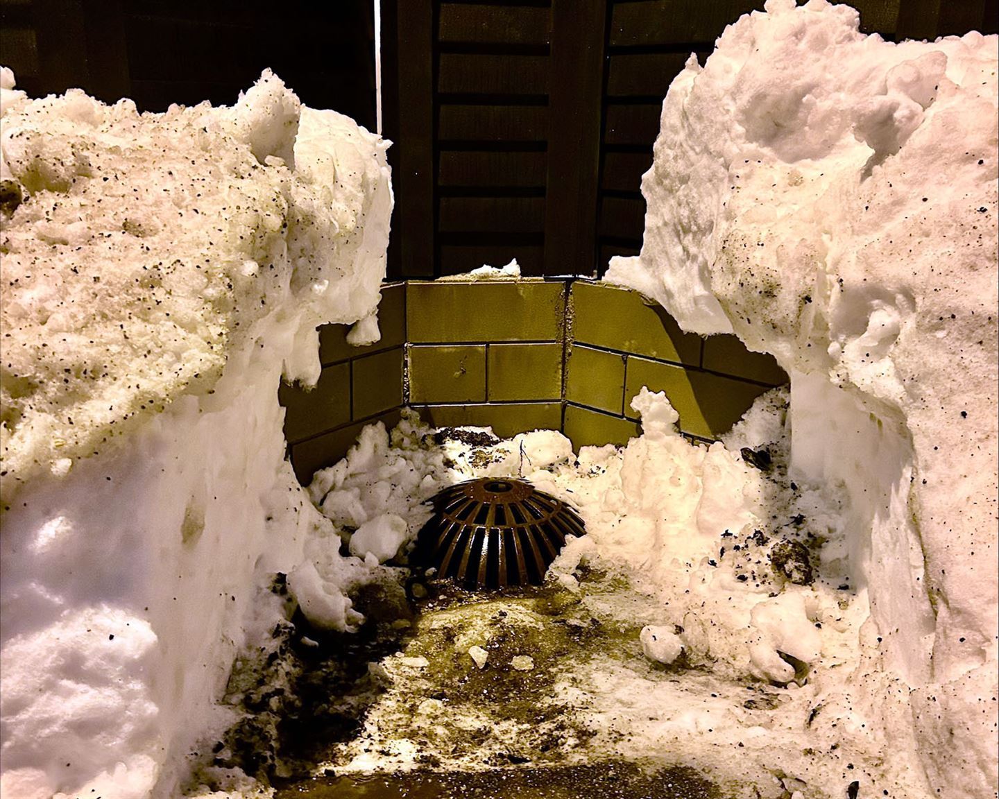 Sandfangkum i Bergen sentrum, omringa av mykje snø, høge snøkantar rundt. sjølve kummen er frigjort for snø.