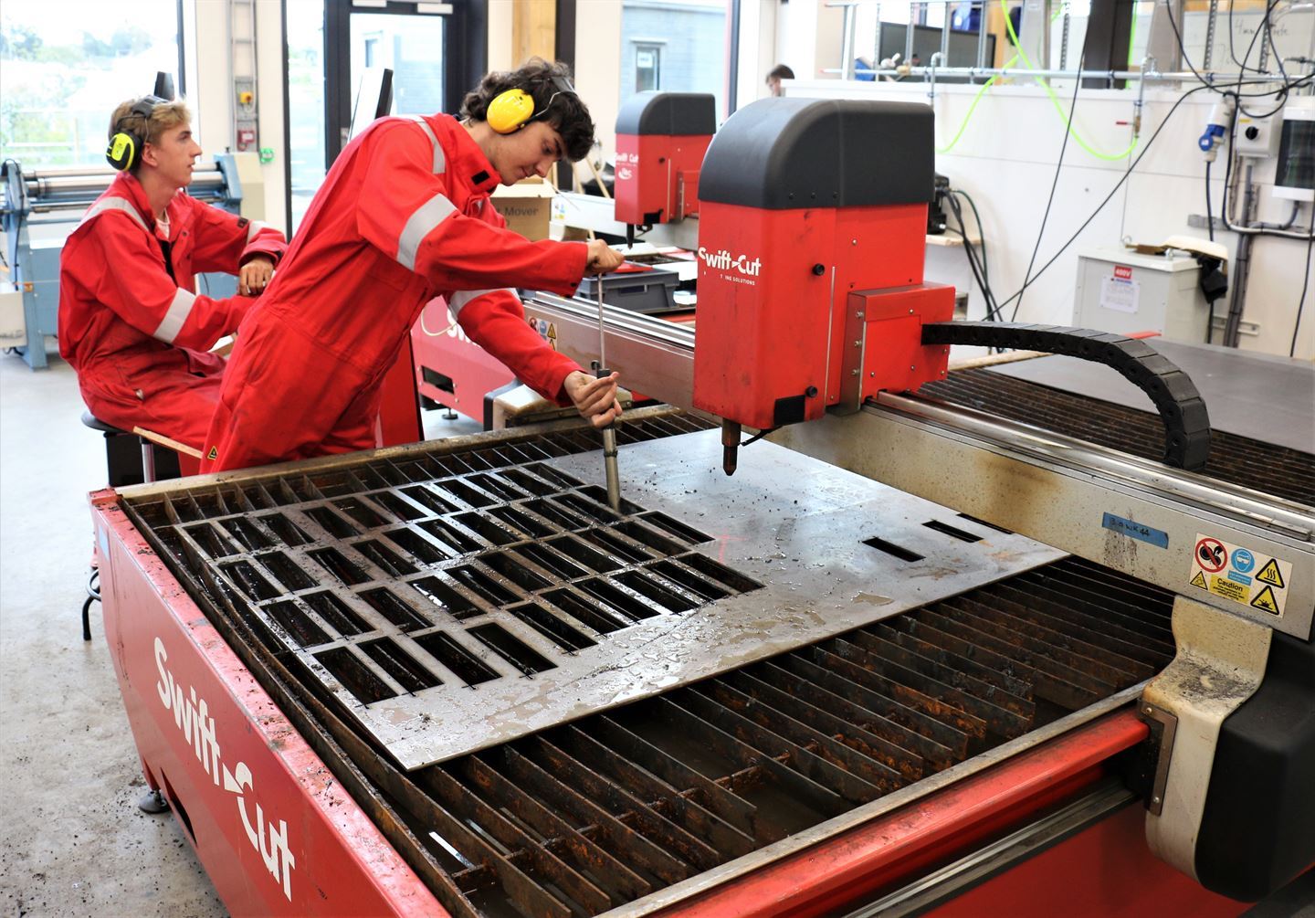 To elevar ved maskin på verkstad