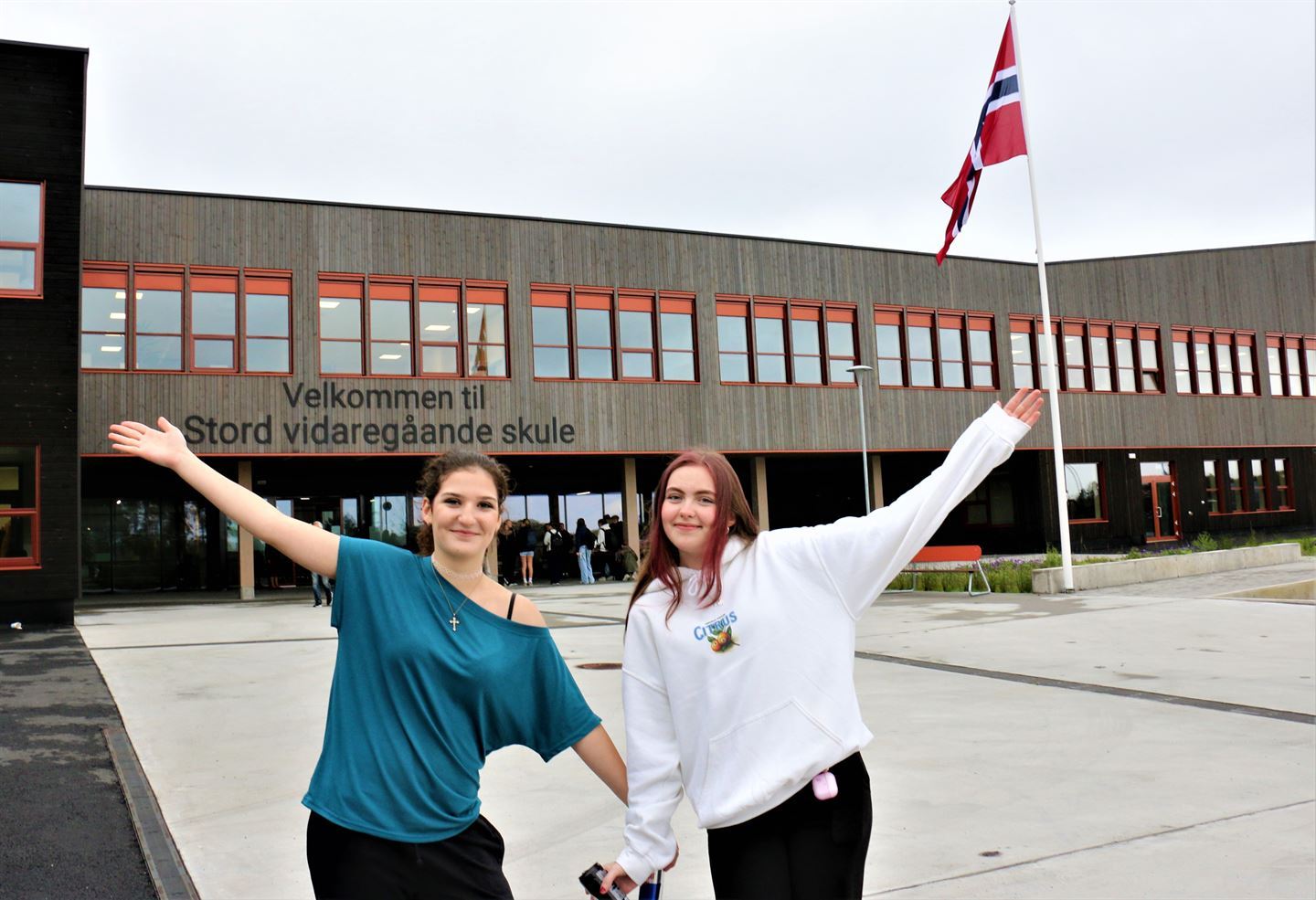 To jenter som jubler framføre stor bygning.