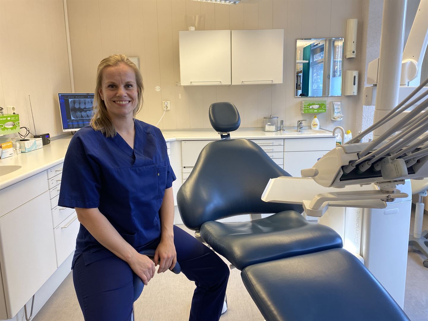 klinikkleiar Dorte Grønsberg sitter ved siden av tannlegestol.