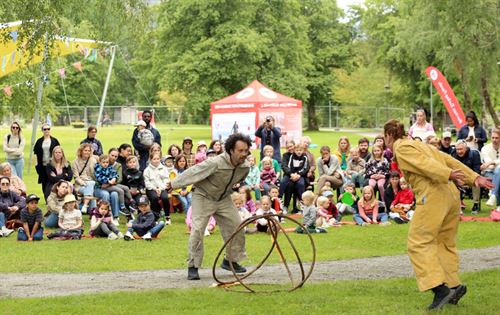 Teaterframsyning på graset i ein park med to kunstnarar og mange ungar i publikum.