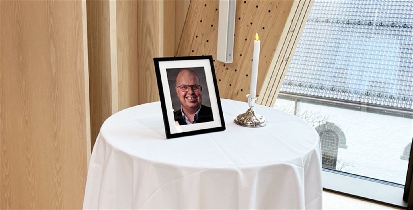 Rundt bord med kvit duk, eit levande lys og innramma bilde av avdøydde fylkestingsmedlem Sigurd Reksnes.