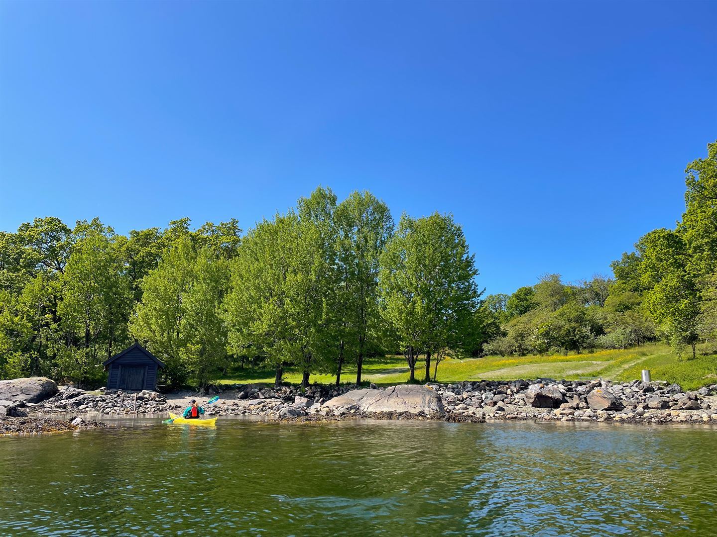 foto av strand og naust, sett frå sjøen.