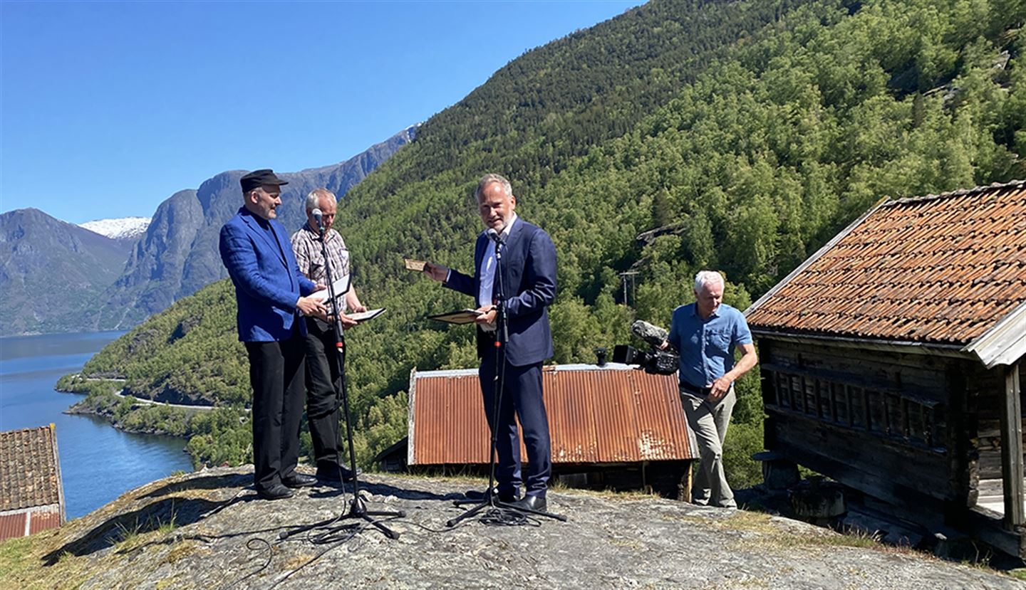 To menn får overrekt plakett av anna mann.