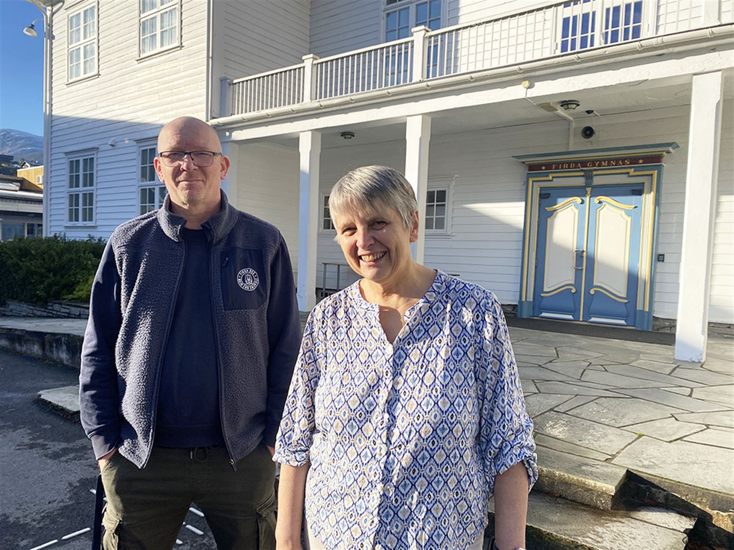 Berit Tesaker og Magne Larsen framfor den gamle hovudbygningen til Firda gymnas på Sandane. 