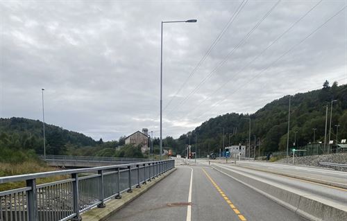 Grå asfalt på gang og sykkelveg. i midten er ei kvit stripe, til høgre er ei gul stripe. Betongklossar skil gang og sykkelvegen frå bilvegen som er heilt til høgre i bildet. 
