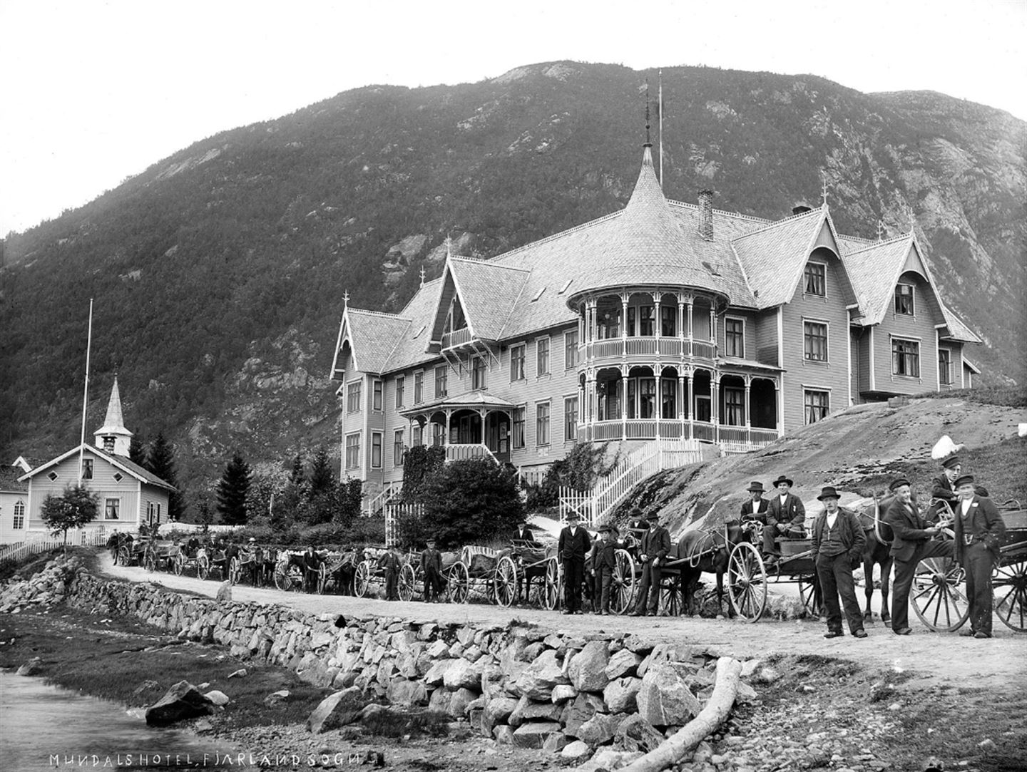Svart-kvitt-bilde av mange hesteskyssvogner oppstilte framfor Hotell Mundal i Fjærland.
