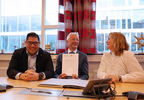 foto av tre personar som sit ved eit bord