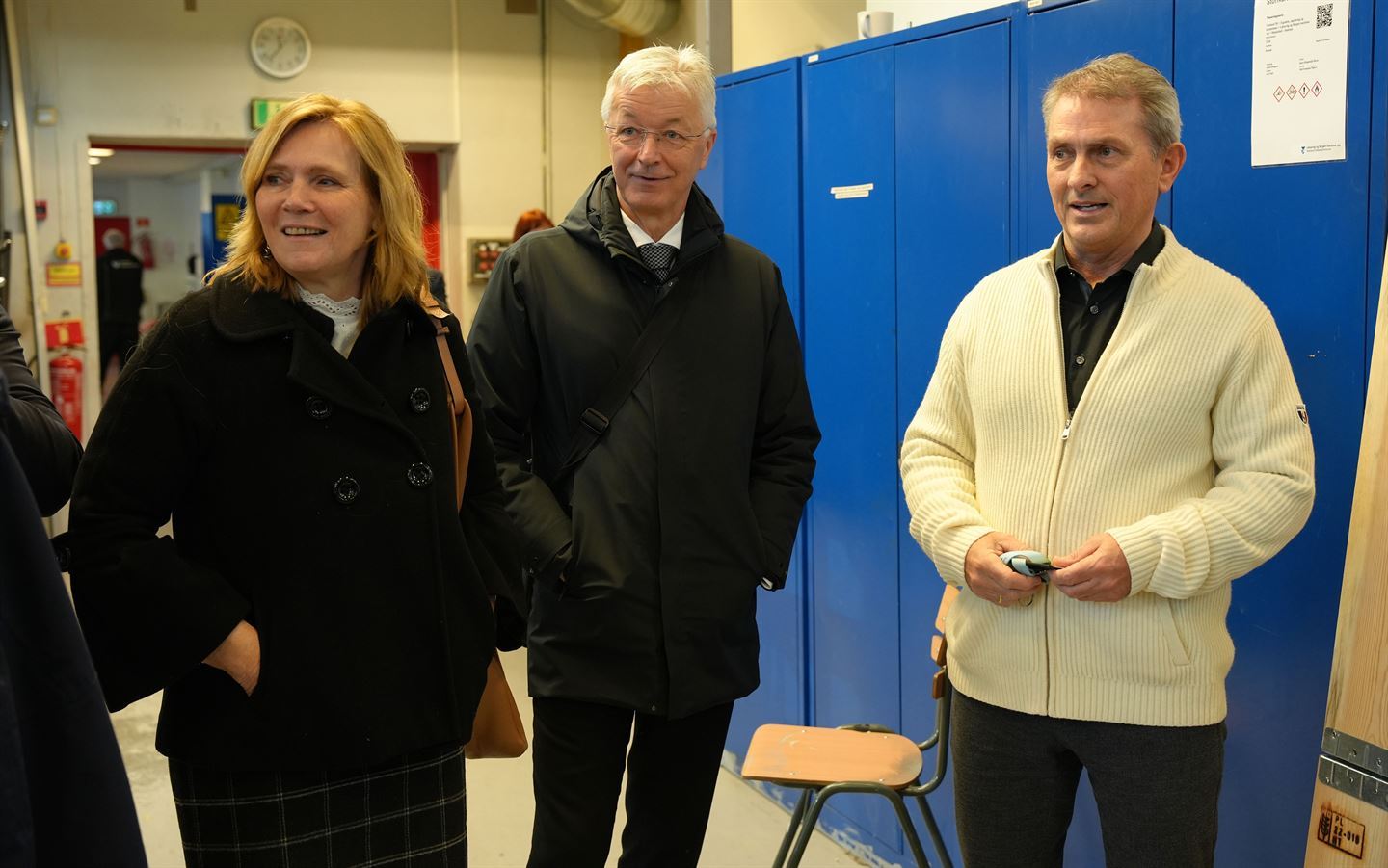 foto av tre personar som strå og snakkar