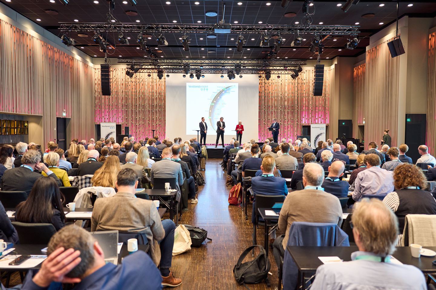 foto av sal med mange folk og ein scene