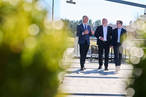foto av tre personar som går medan dei snakkar.