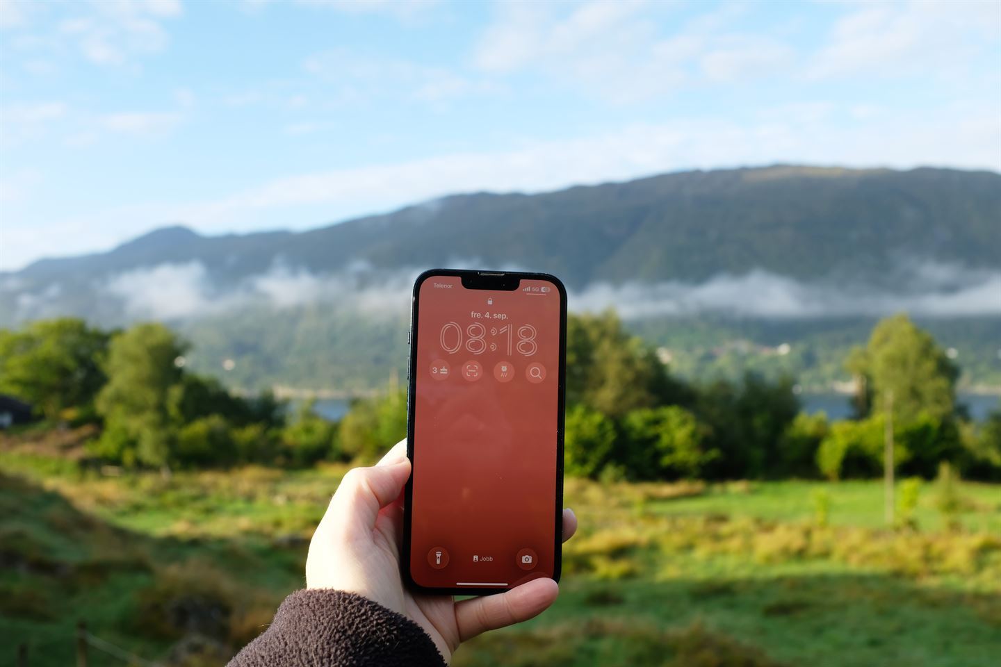 foto av hand som held oppe mobil i natur