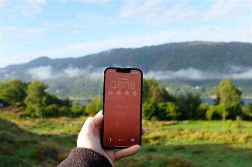 foto av hand som held oppe mobil i natur