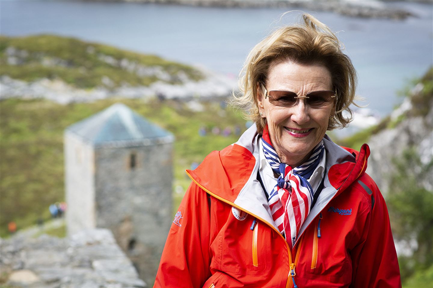 Dronning Sonja på nedsida av St. Sunnivahola, med Selja kloster i bakgrunnen.