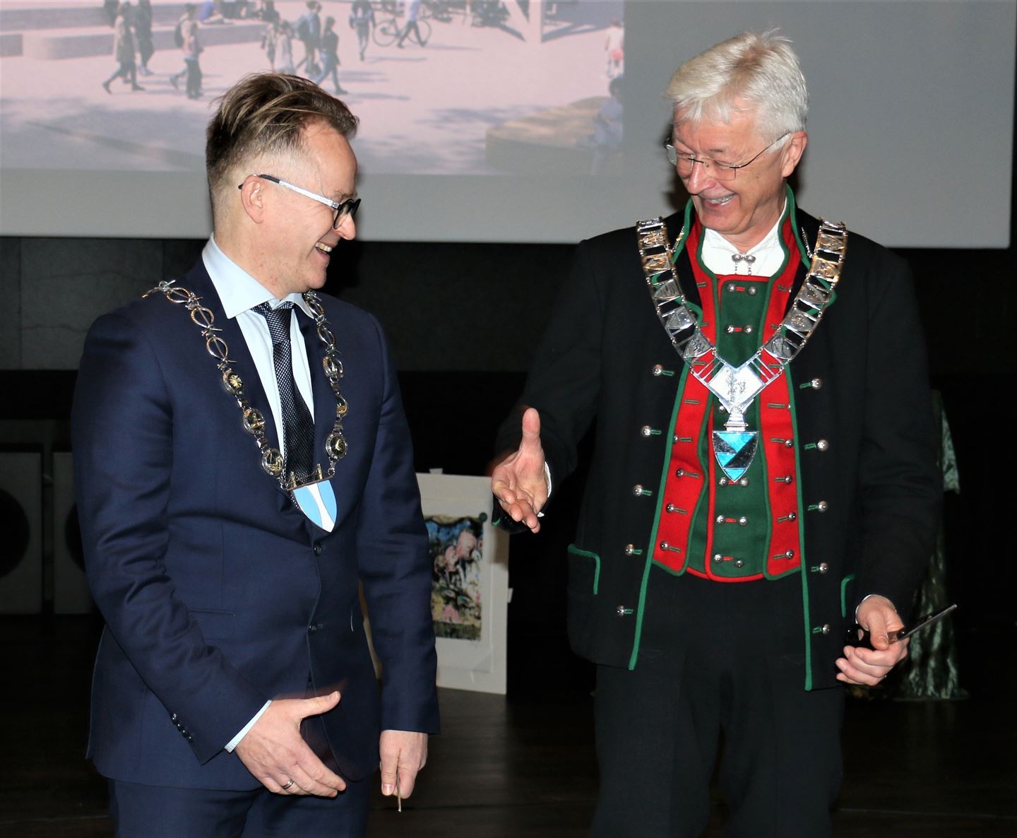 To personar i bunad helsar på kvarandre