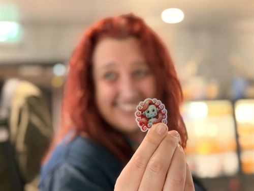 dame med langt rødt hår holder klistremerke av illustrasjon av en robot med langt rødt hår som ligner henne.