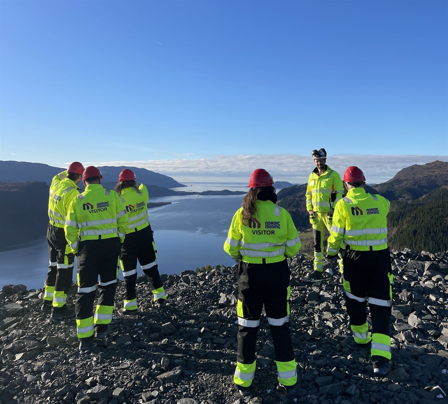 foto av folk som står på eit fjell, arbeidsklede