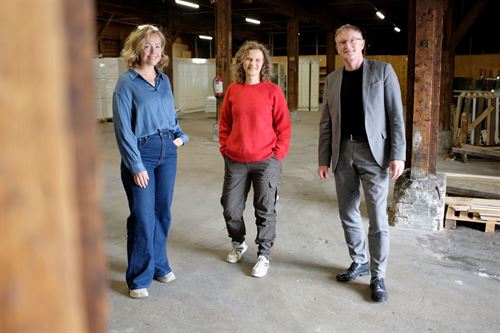 foto av tre personar som står inne i ein hall